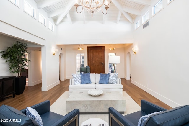 living room with hardwood / wood-style floors, beamed ceiling, a chandelier, a high ceiling, and wood ceiling