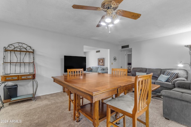 dining space featuring ceiling fan, light carpet, and a textured ceiling