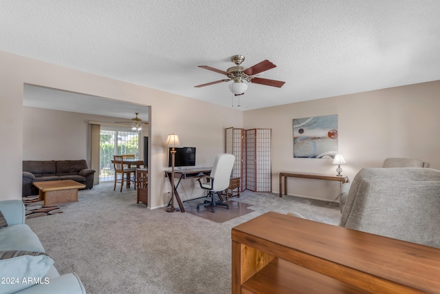 carpeted office space featuring ceiling fan and a textured ceiling