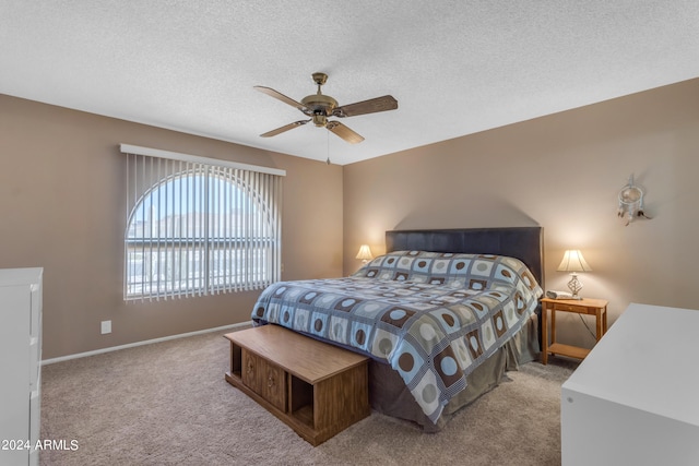 bedroom with ceiling fan, light colored carpet, and a textured ceiling