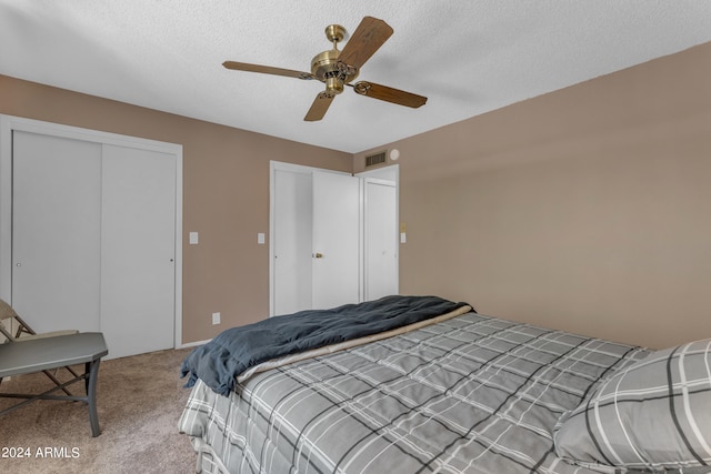 carpeted bedroom with ceiling fan and a textured ceiling