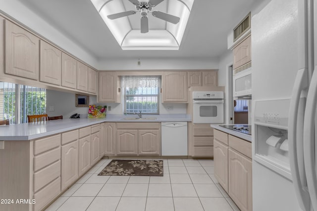 kitchen with white appliances, a tray ceiling, light brown cabinetry, and sink