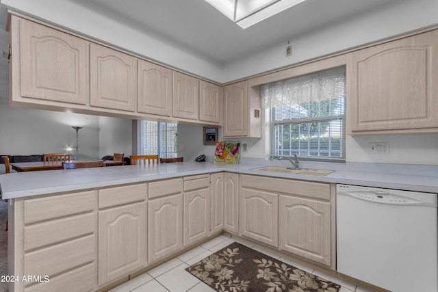 kitchen featuring sink, a skylight, light tile patterned floors, white dishwasher, and kitchen peninsula