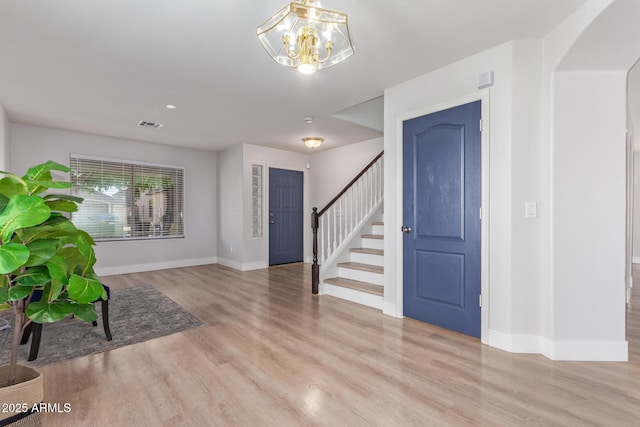foyer entrance with wood finished floors, baseboards, an inviting chandelier, and stairs