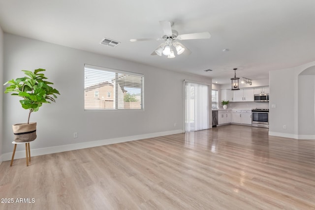 unfurnished living room with baseboards, a ceiling fan, visible vents, and light wood-style flooring