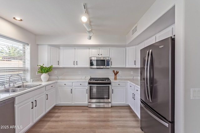 kitchen with white cabinets, a sink, visible vents, light wood-style floors, and appliances with stainless steel finishes
