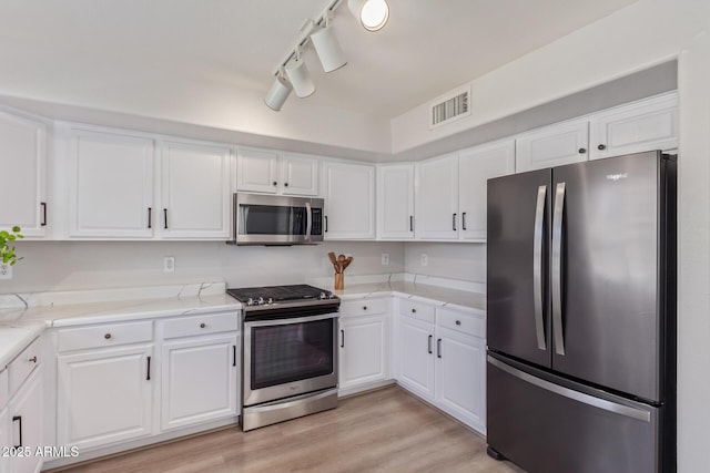 kitchen featuring stainless steel appliances, visible vents, light wood-style floors, and white cabinetry