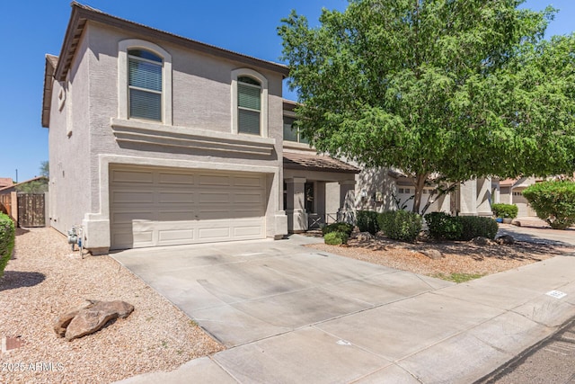 view of front of home with concrete driveway, a tiled roof, an attached garage, fence, and stucco siding