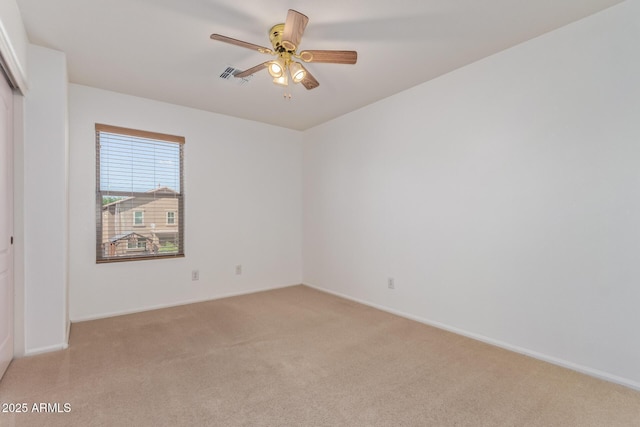 unfurnished room featuring baseboards, visible vents, a ceiling fan, and light colored carpet