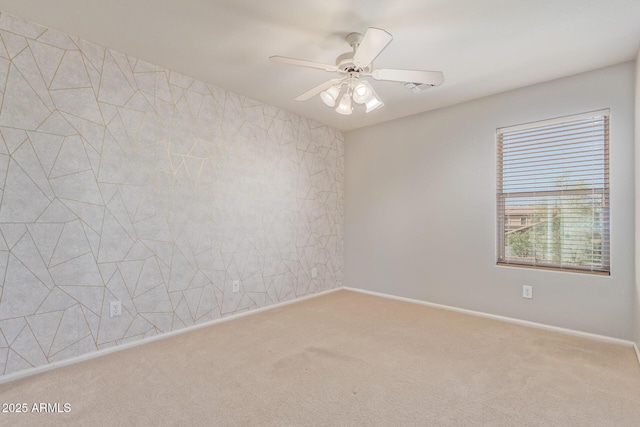 empty room featuring carpet, a ceiling fan, and baseboards