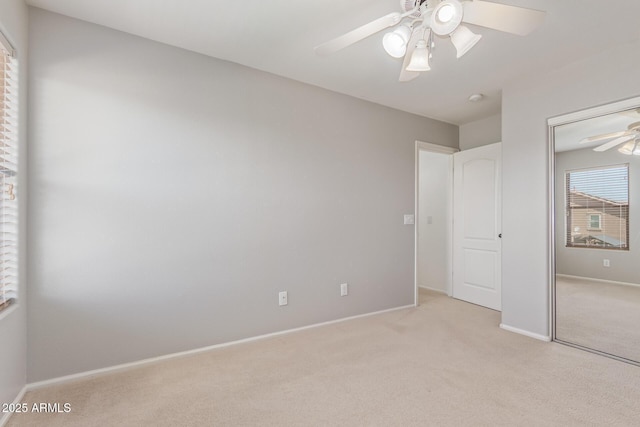 unfurnished bedroom with a closet, light carpet, a ceiling fan, and baseboards