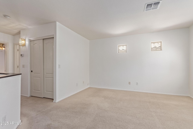 spare room featuring baseboards, visible vents, and light colored carpet