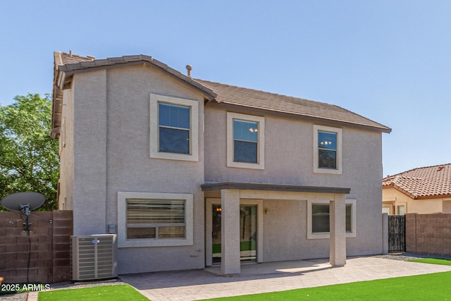 rear view of property featuring a tile roof, a patio area, central air condition unit, fence, and stucco siding