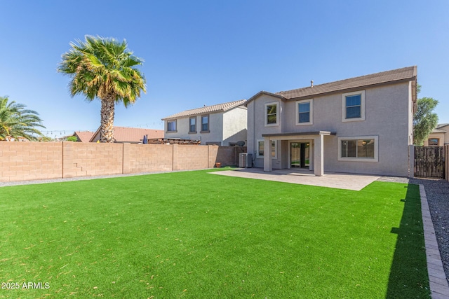 rear view of property featuring a fenced backyard, a yard, central air condition unit, stucco siding, and a patio area