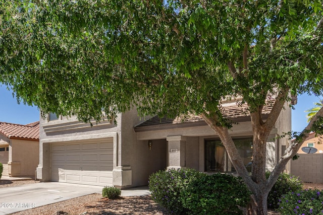 view of front facade with driveway, a tiled roof, an attached garage, fence, and stucco siding