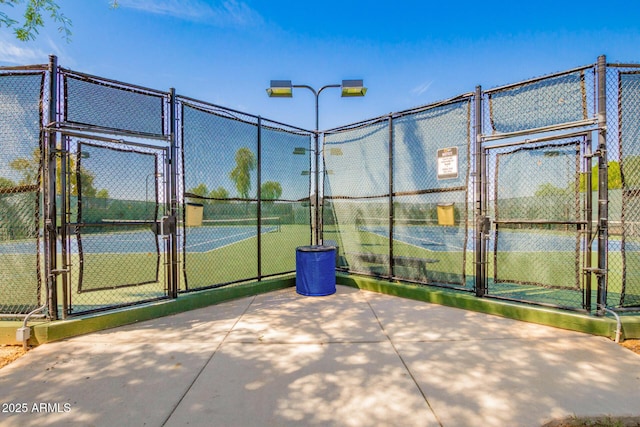 view of tennis court with a gate and fence