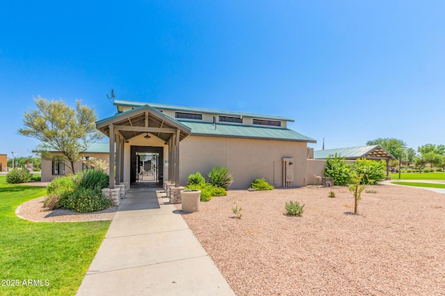 view of front of property featuring a front lawn, metal roof, and stucco siding