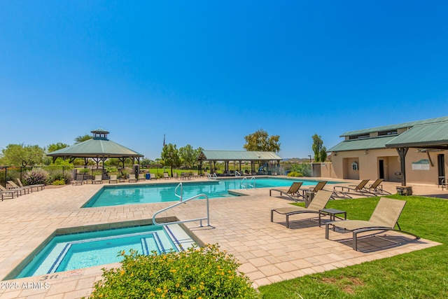 community pool with a gazebo, a patio area, a lawn, fence, and a hot tub