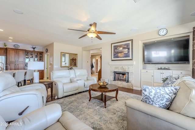 living room featuring ceiling fan, a high end fireplace, and light hardwood / wood-style flooring