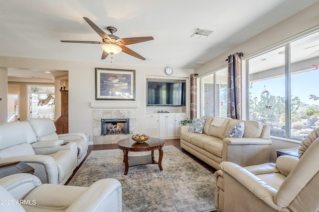 living room featuring ceiling fan, wood-type flooring, and a tile fireplace