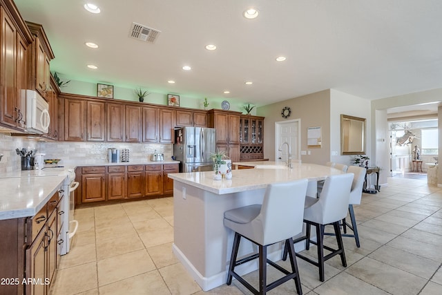 kitchen with light stone counters, a breakfast bar, white appliances, and a large island