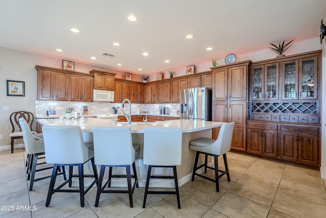 kitchen featuring a breakfast bar, backsplash, stainless steel fridge, and a large island