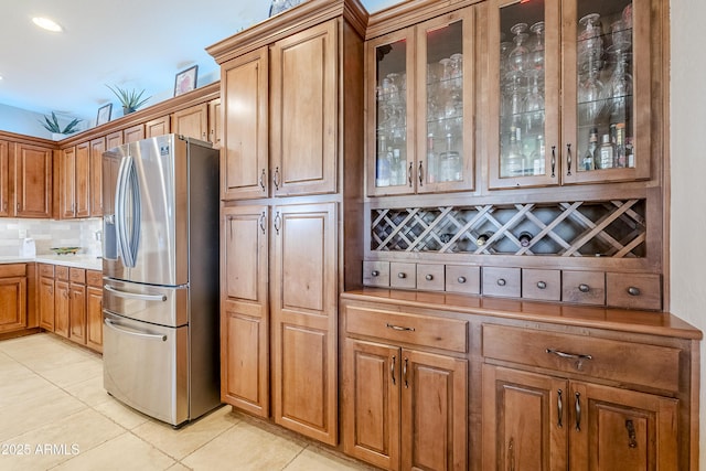 kitchen with light tile patterned floors, decorative backsplash, and stainless steel fridge