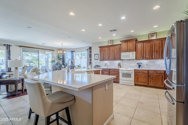 kitchen with backsplash, white appliances, a kitchen breakfast bar, a chandelier, and pendant lighting