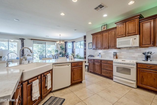 kitchen with an inviting chandelier, tasteful backsplash, white appliances, pendant lighting, and sink