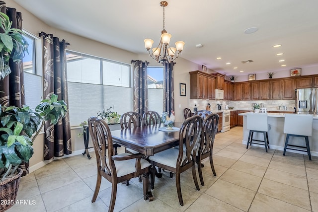 dining space with light tile patterned flooring, plenty of natural light, and an inviting chandelier