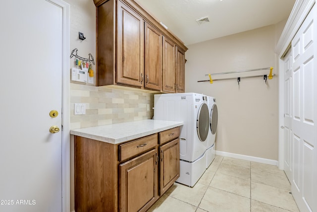 laundry area featuring washer and dryer, cabinets, and light tile patterned flooring