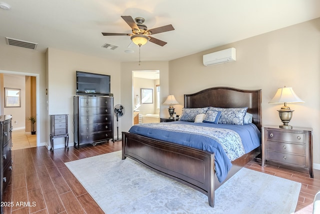 bedroom with ceiling fan, an AC wall unit, and ensuite bath