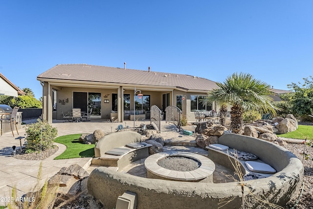 rear view of property featuring a patio area and a fire pit