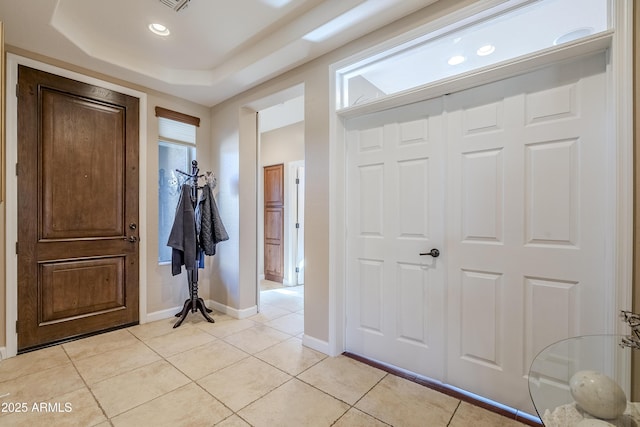 entrance foyer with light tile patterned flooring and a tray ceiling