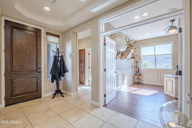 entryway with light tile patterned flooring and a raised ceiling