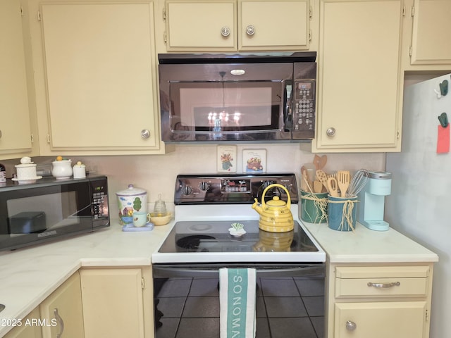1118 E Orangewood Ave, Phoenix, AZ 85020 - kitchen with range with electric stovetop, cream cabinets, light countertops, and black microwave