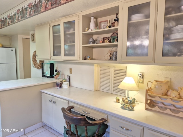 1118 E Orangewood Ave, Phoenix, AZ 85020 - kitchen with light countertops, glass insert cabinets, light tile patterned floors, and freestanding refrigerator