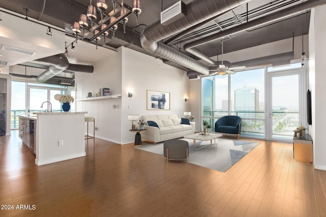 living room featuring rail lighting, dark hardwood / wood-style floors, ceiling fan, and a wall of windows