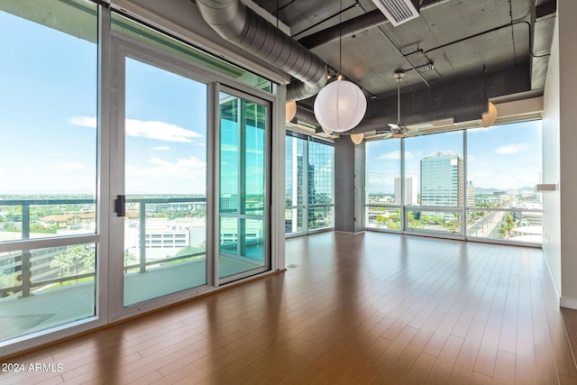 empty room with expansive windows, a healthy amount of sunlight, and hardwood / wood-style floors