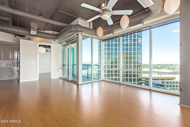 unfurnished room featuring floor to ceiling windows, hardwood / wood-style floors, and ceiling fan