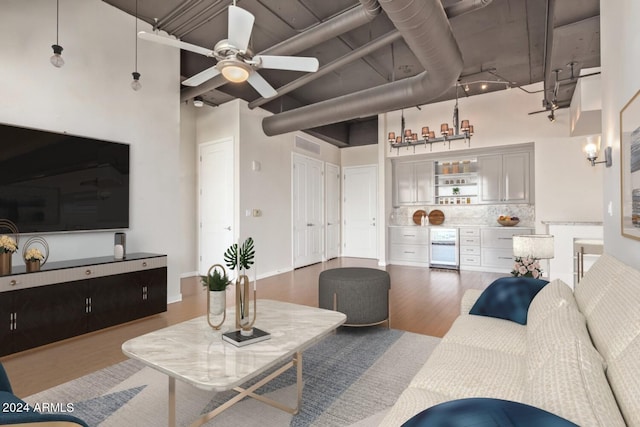 living room with hardwood / wood-style flooring, ceiling fan, and a high ceiling