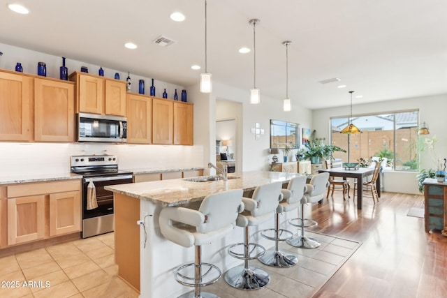 kitchen with light brown cabinets, visible vents, appliances with stainless steel finishes, and a wealth of natural light