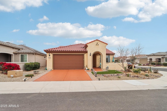 mediterranean / spanish home featuring stucco siding, a tiled roof, an attached garage, and concrete driveway