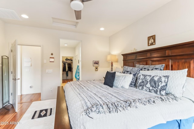 bedroom with attic access, light wood-style flooring, recessed lighting, a closet, and a walk in closet