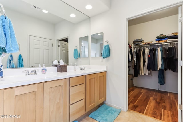 bathroom featuring a sink, visible vents, double vanity, and tile patterned flooring