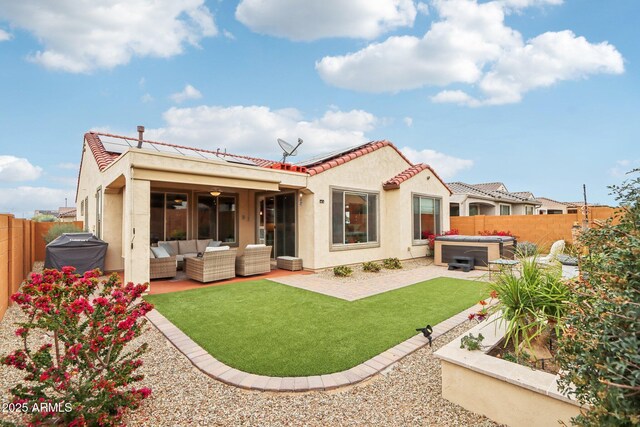 rear view of house featuring an outdoor living space, solar panels, a hot tub, a fenced backyard, and a patio area