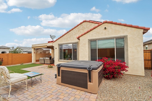 rear view of house with a patio area, a fenced backyard, stucco siding, and a hot tub