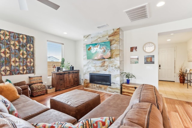 living area featuring a premium fireplace, visible vents, recessed lighting, and wood finished floors