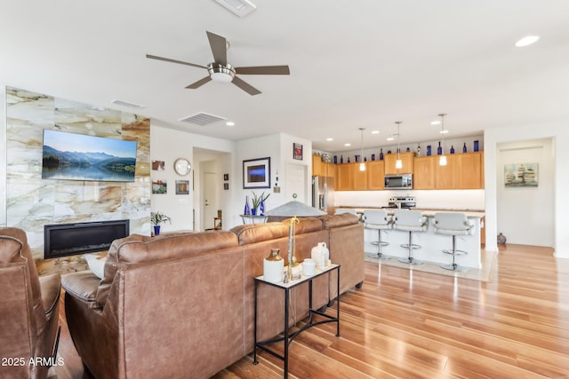 living area with light wood-style flooring, a fireplace, and visible vents