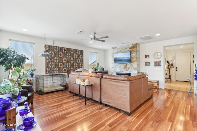 living area with visible vents, a fireplace, and light wood-style floors